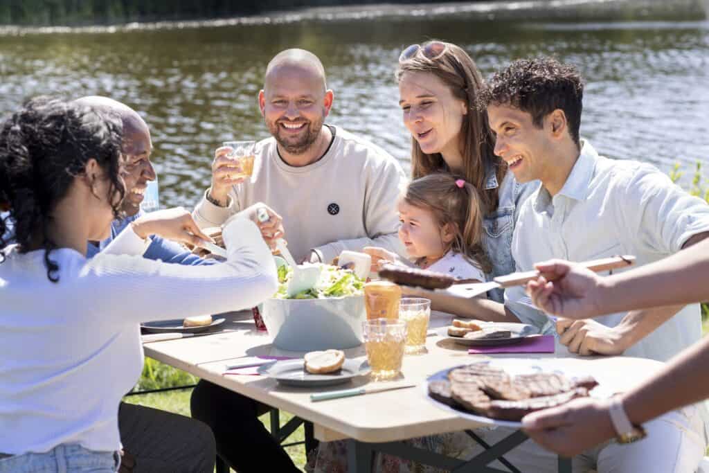 Gezellig buiten eten met familie aan de waterkant, genieten van een zomerse dag.